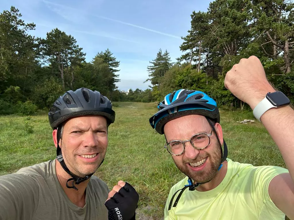 Twee mountainbikers op een zandpad tussen de bomen in de Schoorlse duinen